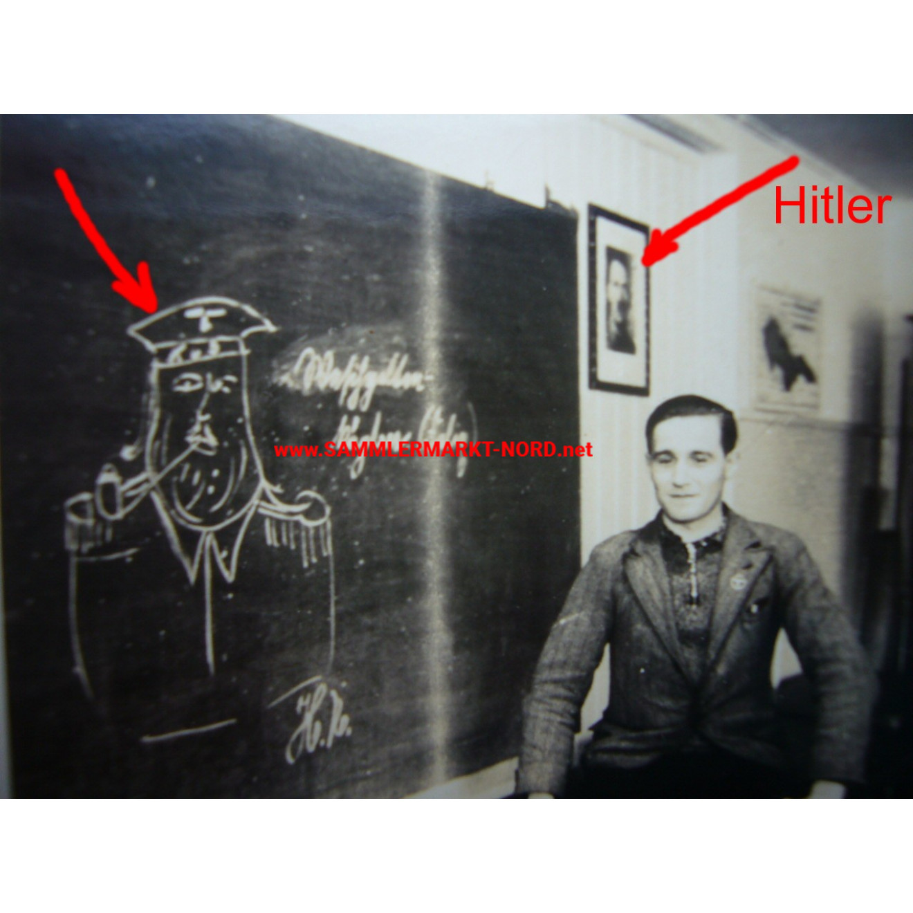 Man in front of blackboard with drawing and Hitler picture on the wall